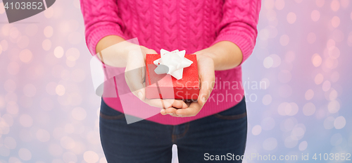 Image of close up of woman in pink sweater holding gift box