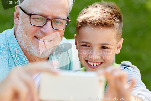 Image of old man and boy taking selfie by smartphone