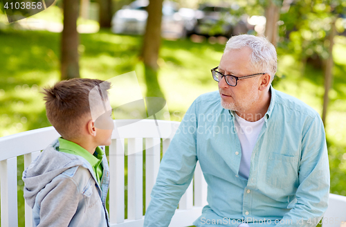 Image of grandfather and grandson talking at summer park