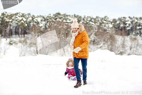 Image of happy father pulling sled with child in winter