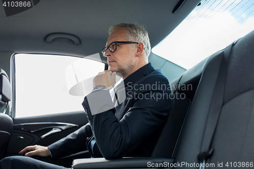 Image of senior businessman driving on car back seat