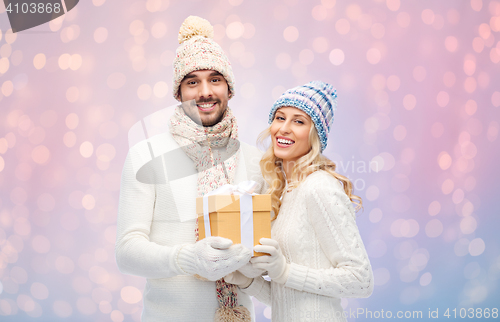 Image of smiling couple in winter clothes with gift box