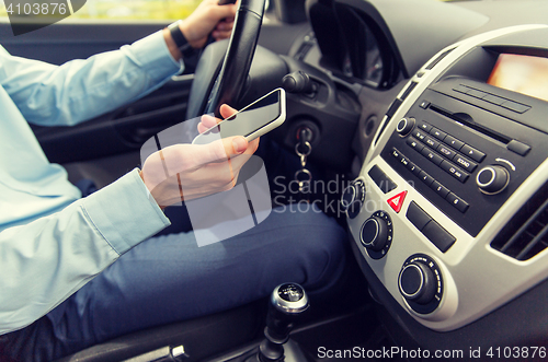 Image of close up of man with smartphone driving car