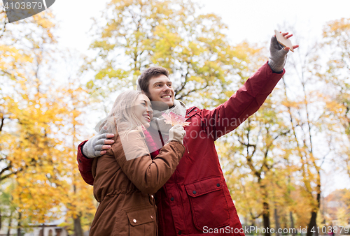 Image of couple taking selfie by smartphone in autumn park