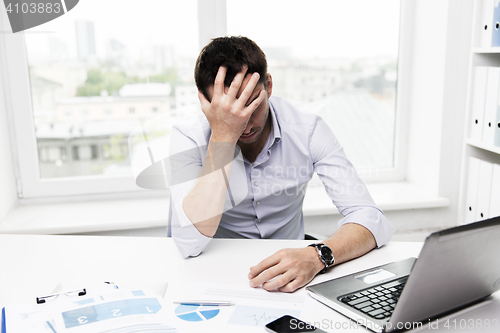 Image of businessman with laptop and papers in office