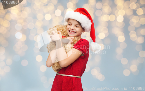 Image of smiling girl in santa helper hat with teddy bear