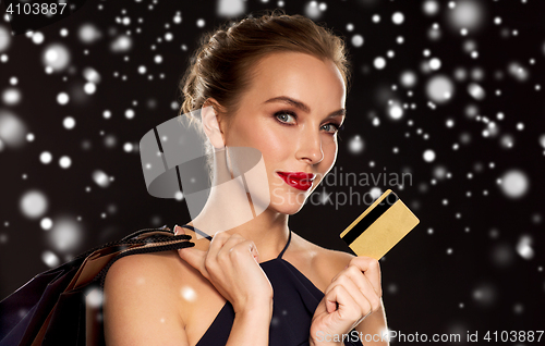 Image of woman with credit card and shopping bags over snow