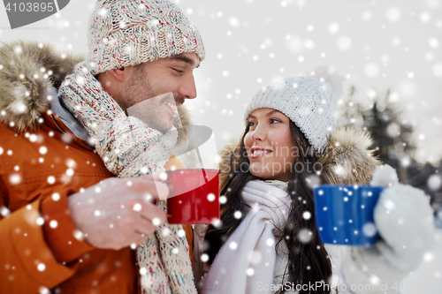 Image of happy couple with tea cups over winter landscape