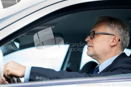 Image of happy senior businessman driving car