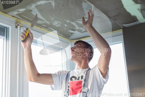 Image of Plasterer renovating indoor walls and ceilings. Finishing works.