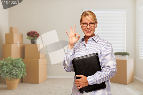 Image of Woman with Okay Sign in Empty Room with Packed Moving Boxes