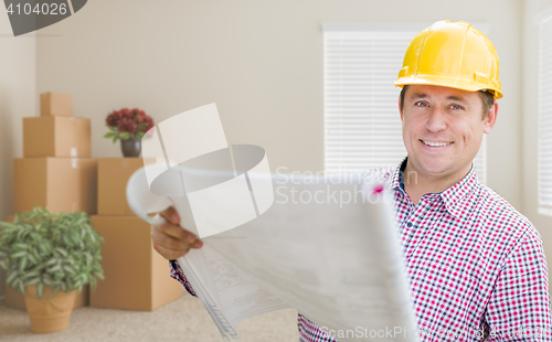Image of Male Construction Worker In Room With Boxes Holding Roll of Blue