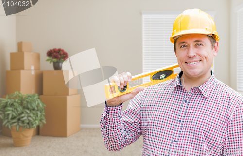 Image of Male Construction Worker In Room With Moving Boxes Holding Level