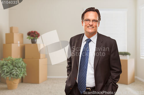 Image of Businessman in Empty Room with Packed Boxes and Plants