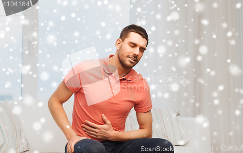 Image of unhappy man suffering from stomach ache at home