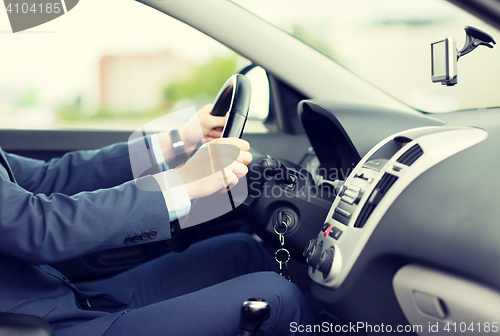 Image of close up of young man in suit driving car