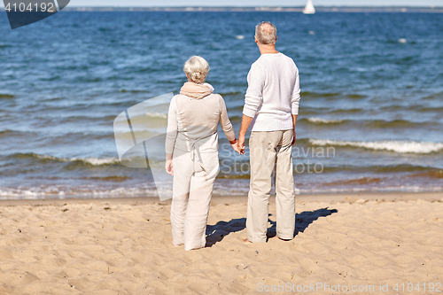 Image of happy senior couple holding hands summer beach