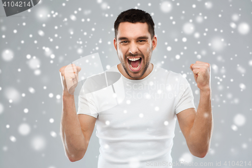 Image of angry young man holding fists over snow