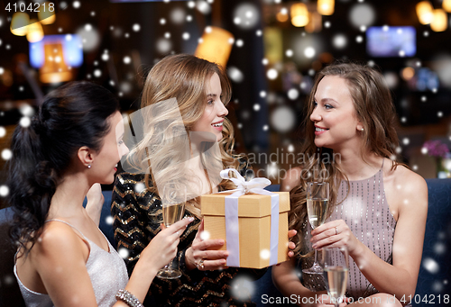 Image of happy women with champagne and gift at night club