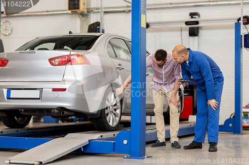 Image of auto mechanic with clipboard and man at car shop