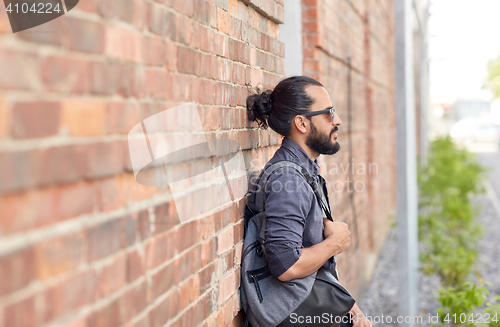 Image of man with backpack standing at city street wall