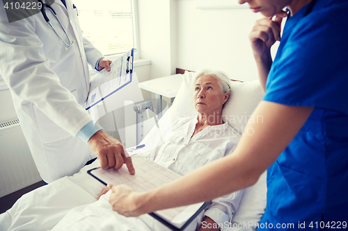 Image of doctor and nurse visiting senior woman at hospital