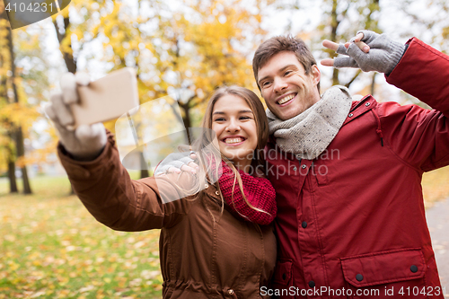 Image of couple taking selfie by smartphone in autumn park