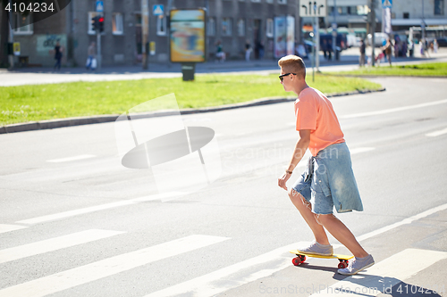 Image of teenage boy on skateboard crossing city crosswalk