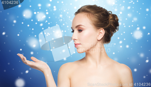 Image of woman holding something on palm over snow