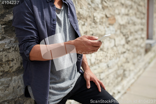 Image of close up of man with smartphone at stone wall