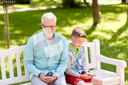 Image of old man and boy with smartphones at summer park