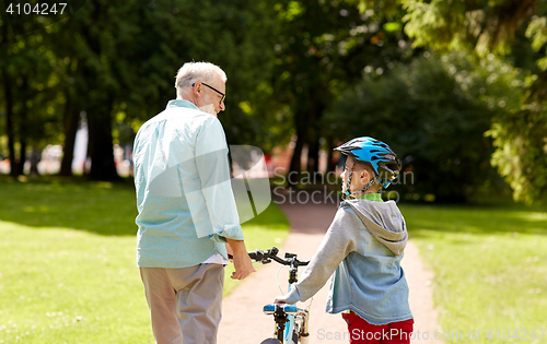 Image of grandfather and boy with bicycle at summer park