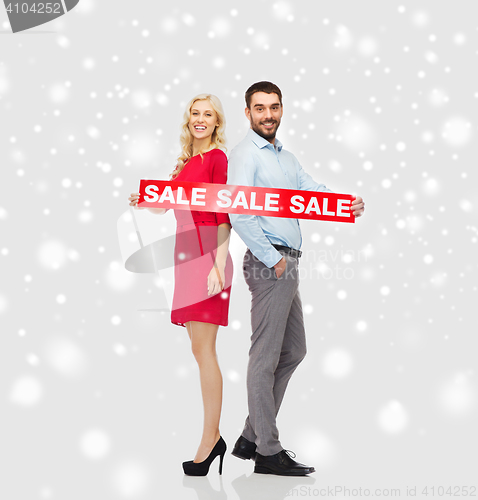 Image of happy couple with red sale sign over snow