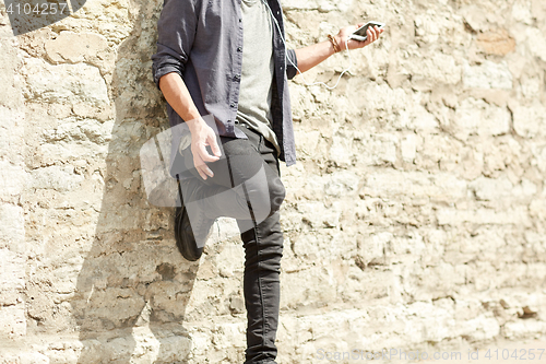 Image of man with earphones and smartphone on street