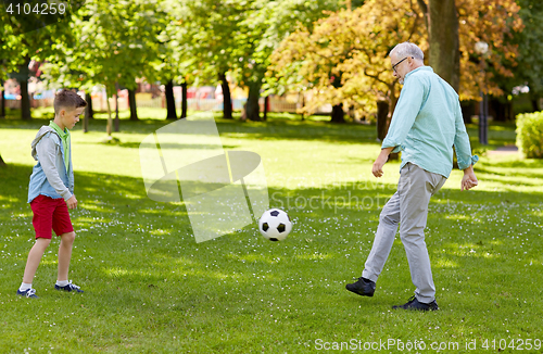 Image of old man and boy playing football at summer park