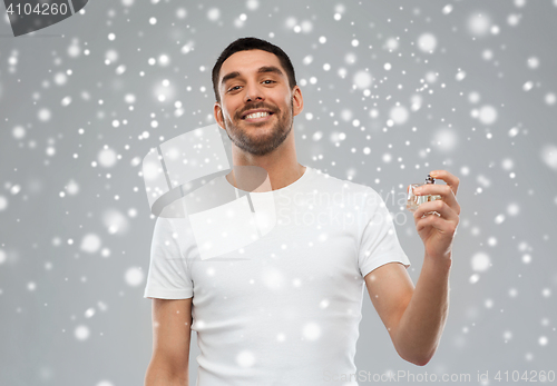 Image of smiling man with male perfume over snow background