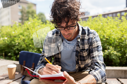 Image of man with notebook or diary writing on city street