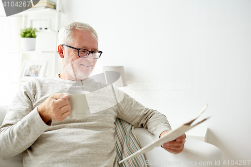 Image of senior man in glasses reading newspaper at home