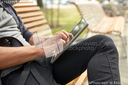 Image of close up of man with tablet pc sitting on bench