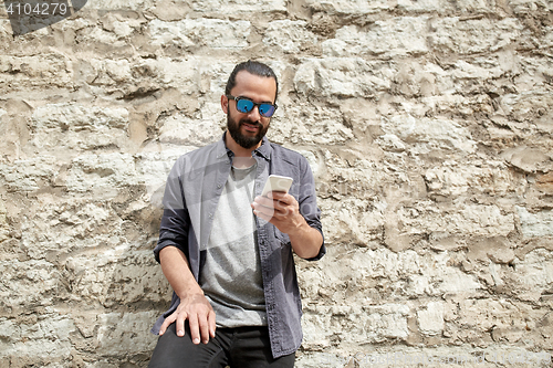 Image of man texting message on smartphone at stone wall