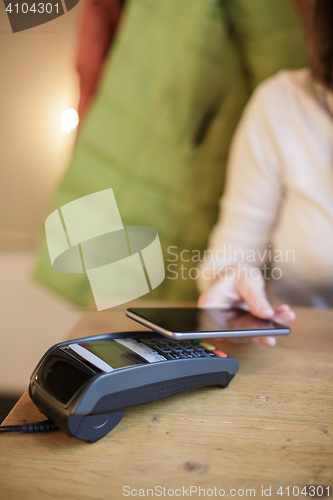 Image of Woman pays the bill in the cafe with their smartphone