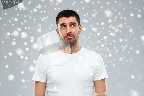 Image of unhappy young man over snow background