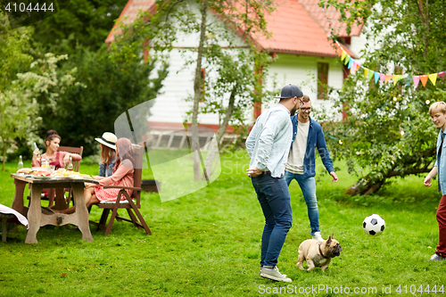 Image of friends playing football with dog at summer garden