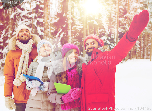 Image of smiling friends with tablet pc in winter forest