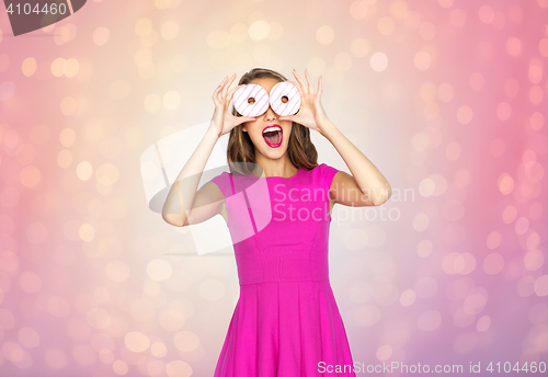 Image of happy woman or teen girl having fun with donuts