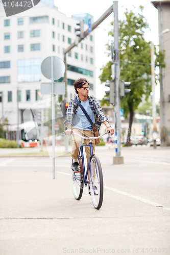 Image of young hipster man with bag riding fixed gear bike