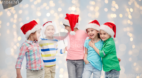 Image of happy little children in santa hats hugging