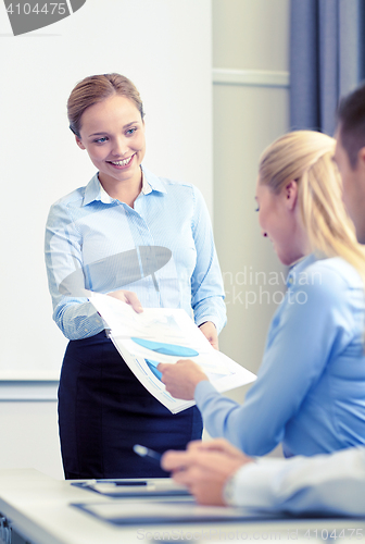 Image of woman giving papers to group of businessmen