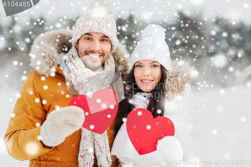 Image of happy couple with red hearts over winter landscape