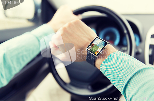 Image of close up of male hands with smartwatch driving car